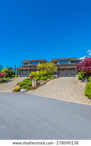 Big custom made luxury house with nicely landscaped front yard and paved driveway to garage in the suburbs of Vancouver, Canada. Vertical.