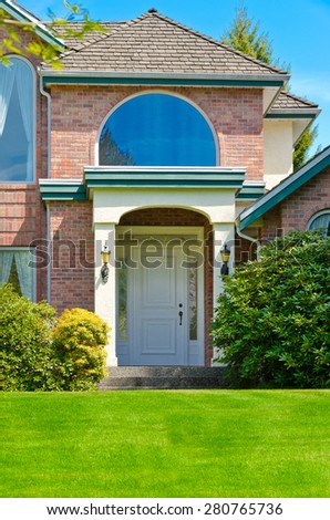 House entrance with nicely trimmed and landscaped front yard. Vertical.
