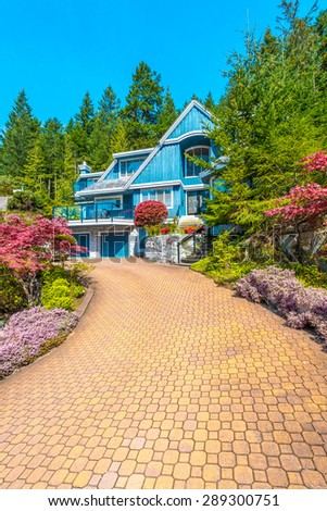Custom built luxury house with nicely trimmed front yard, lawn and paved driveway to garage in a residential neighborhood. Vancouver Canada. Vertical.