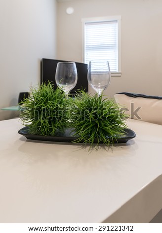 Coffee table with two wine glasses and some decorative plants and TV set as a background. Interior design. Vertical.