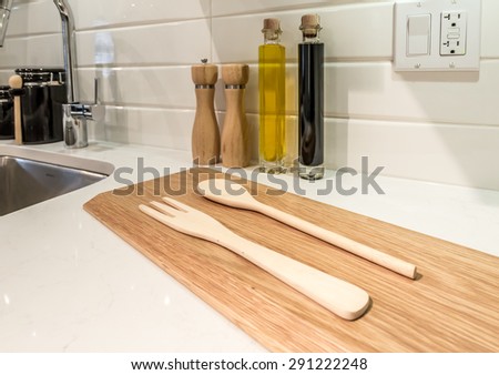 Cutting desk with wooden spoon and fork  and salt and pepper mills and oil and vinegar containers  as a decorative element of the luxury modern kitchen. Interior design.