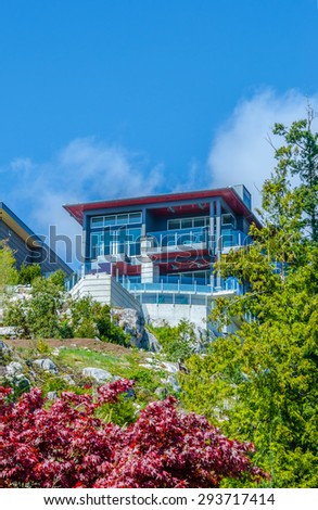 Big custom built luxury modern house on the rocks, cliff with nicely landscaped front yard in the residential neighborhood of Vancouver, Canada. Vertical.