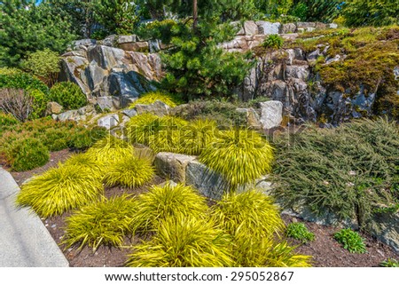 Flowers, stones and nicely trimmed bushes in front of the house, front yard. Landscape design.