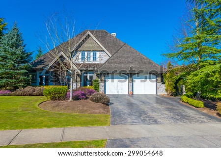 Big custom made luxury modern house with paved driveway and  nicely landscaped front yard in the suburbs of Vancouver, Canada.