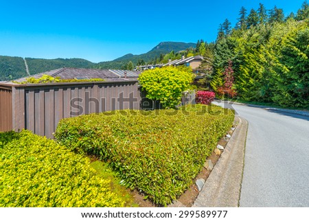 Nicely trimmed bushes  in front of the house, front yard on the empty street. Landscape design.