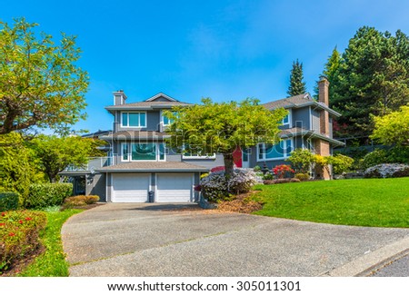 Big custom made luxury house with nicely landscaped front yard and  driveway to the garage in the suburbs of Vancouver, Canada.