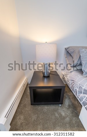 Night stand with the lamp on it at the bed of modern comfortable and elegant luxury master bedroom. Interior design.