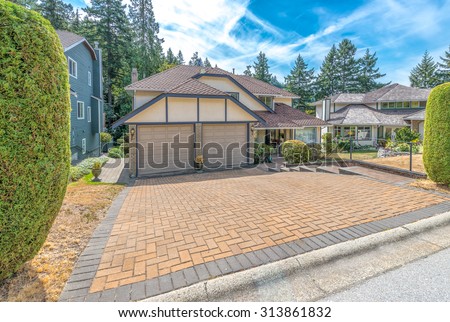Big custom made luxury house with nicely paved driveway to garage and trimmed front yard in the suburbs of Vancouver, Canada.