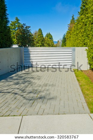 Modern gates with nicely paved driveway. driveway. North America. Vertical.
