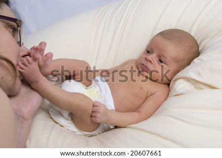 Newborn Baby Boy Joshua Kailas Hudson Lying in Beanbag Looking as Mother Kisses His Foot