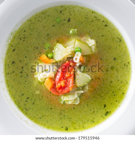 Hot vegetarian healthy soup with pesto sauce, noodles and vegetables in a round plate