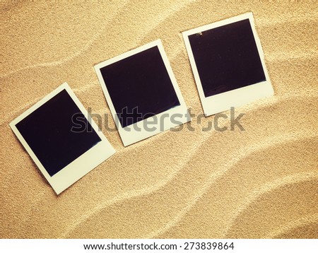 Empty photo cards in retro style  lying on a sea sand. Sunny summer background. Space for your text.