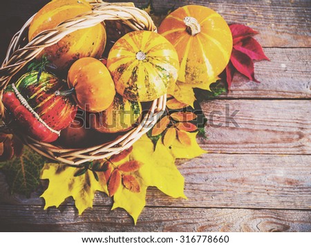 Autumn background with colorful leaves and pumpkins on rustic wooden board. Gifts of Autumn in a basket. Thanksgiving and Halloween holidays concept. Harvest rural fall season. Space for your text.