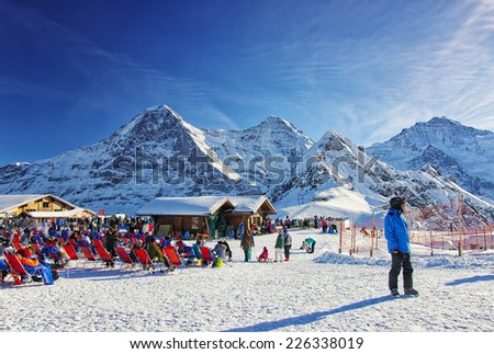 MAENNLICHEN, SWITZERLAND - DECEMBER 31, People at the outdoor lounge on highland winter sport resort in swiss alps on December 31, 2013 in swiss Jungfrau region