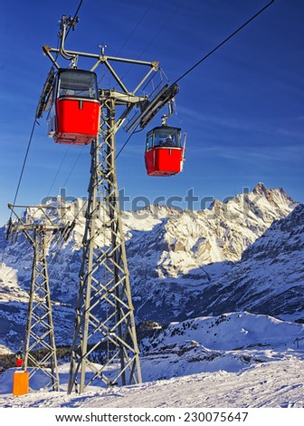 Red cable cars on the cable railway on winter sport resort in swiss alps on sunshine