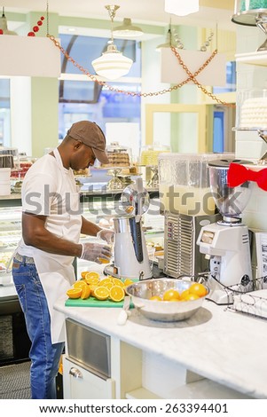 Black man extracting orange juice at cafe counter