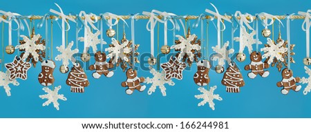 Horizontal seamless texture of Christmas garland decorated with gingerbread, crocheted snowflakes and golden bells on a blue background.
