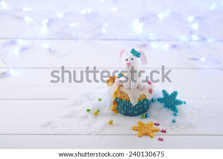 Cupcake decorated a sugar rabbit with blue bow on a bright lights background horizontal format.