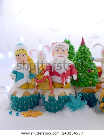 Festive cupcakes decorated with sugar figures of Santa Claus Snow Maiden Christmas tree selective cropping.