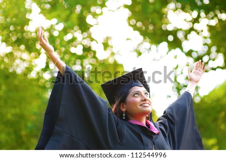 Young Asian Indian female student open arms outdoor on graduation day