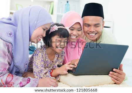 Southeast Asian family browsing internet at home. Lying on floor using computer laptop.