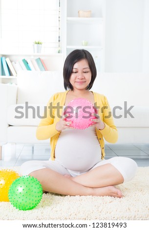 Asian pregnant woman exercising with yoga ball