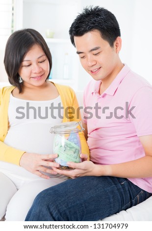 Asian family financial planning concept. Young pregnant couple saving money for future. Living lifestyle at home.