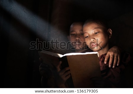 Little monks reading book inside monastery