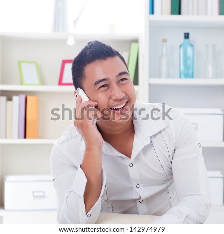 Young Asian man talking on the phone. Lifestyle Southeast Asian man at home. Handsome Asian male model.