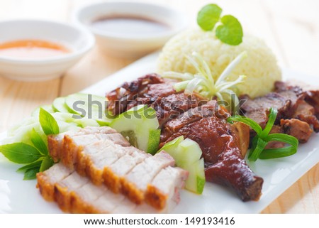 Roasted duck, roasted pork crispy siu yuk and Charsiu Chinese style, served with steamed rice on dining table. Singapore cuisine.