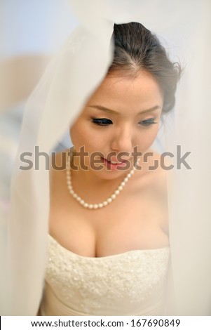 Beautiful Asian bride smiling under the veil on wedding day.