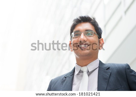 Portrait of happy 30s Asian Indian businessman smiling. India male business man, real modern office building as background.