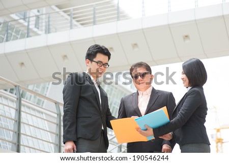 Asian business team meeting, showing report to CEO and having discussion. Modern office background.