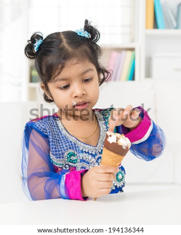 Eating ice cream. Indian Asian girl enjoying an ice cream at home.