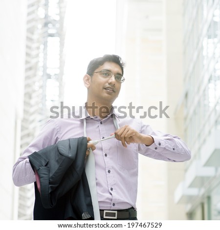 Portrait of a Indian businessman taking off his tie  after working hours, walking at modern building.