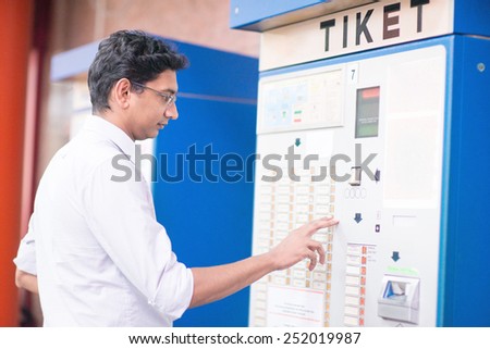 Asian Indian businessman buying transport ticket at vending machine.