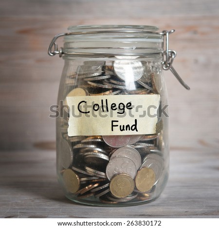Coins in glass jar with college fund label, financial concept. Vintage wooden background with dramatic light.
