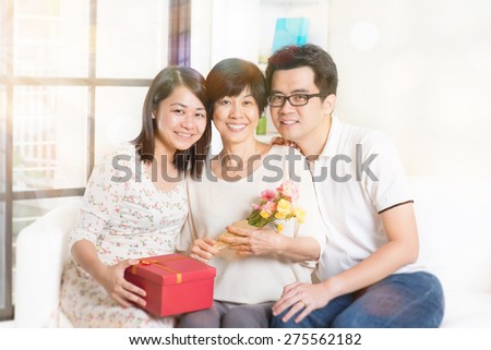 Happy mothers day. Asian senior mom received gift box and flowers from her young children. Family living lifestyle at home.