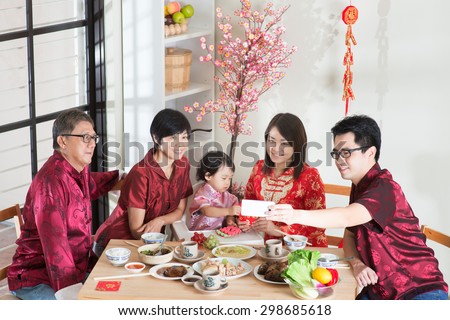 Celebrating Chinese New Year, reunion dinner. Happy Asian Chinese multi generation family with red cheongsam selfie while dining at home.