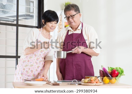 Asian mature couple cooking food at kitchen. Seniors living lifestyle at home.