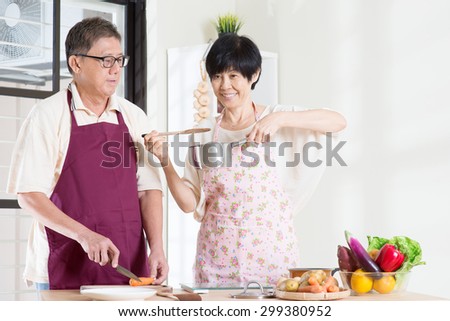 Asian mature couple cooking meal at kitchen. Seniors living lifestyle at home.