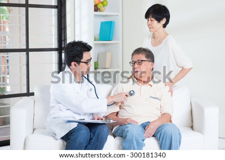 Doctor and patient. Sick Asian old man consult family doctor, sitting on sofa. Senior retiree indoors living lifestyle.