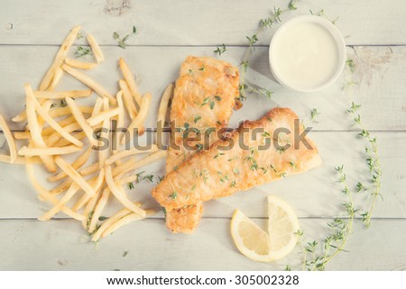 Fish and chips. Above view fried fish fillet with french fries on wooden background, vintage tone.