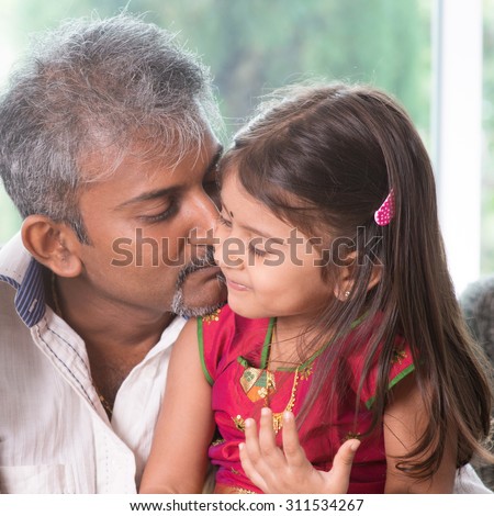 Happy Indian family at home. Asian dad kissing his toddler. Father and daughter indoor lifestyle.
