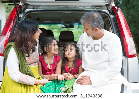 Happy Asian Indian family sitting in car talking and smiling happily, ready to summer vacation.