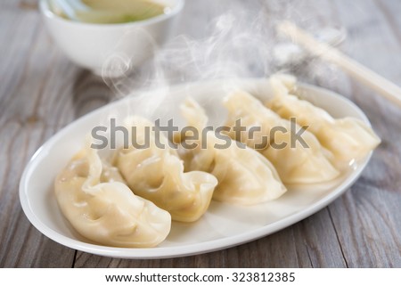 Fresh dumpling on plate. Chinese food with hot steams on old wooden background.