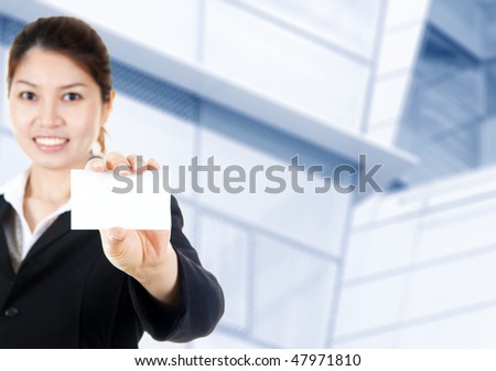 Blank business card. Young Asian with blank business card in a hand, office building as background.