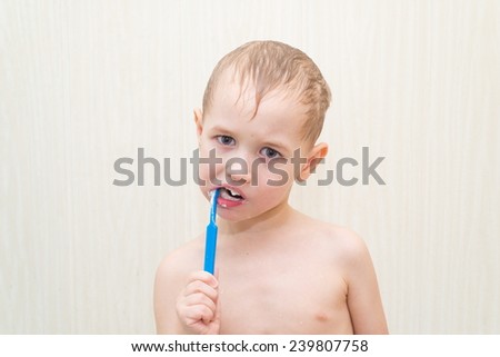 Blond boy brushing his teeth in the bathroom blue brush