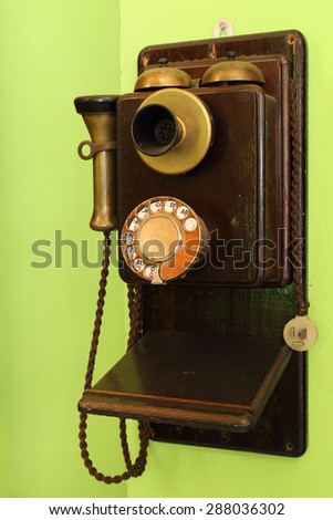 old classic wood telephone hanging on green wall