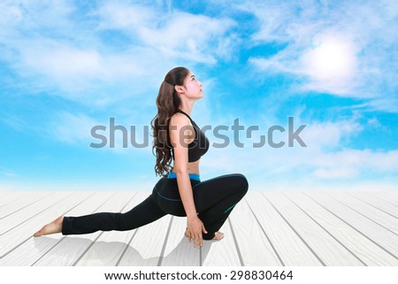 Young woman doing yoga exercise on wood floor with sky